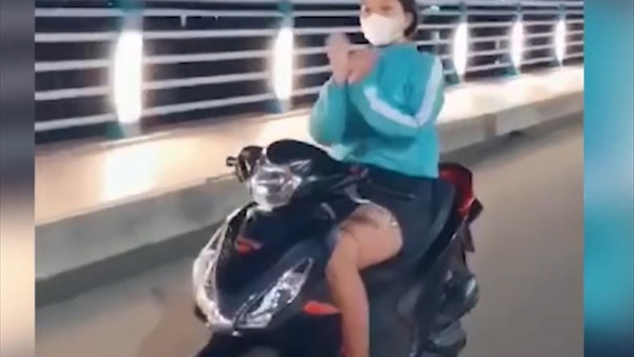 Cô gái trẻ buông tay lái xe máy để… múa quạt! - 1