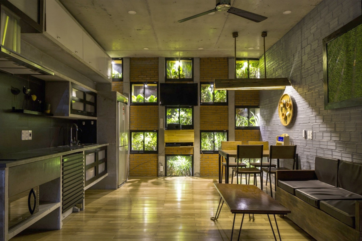 Phòng khách và phòng bếp ăn được tích hợp chung một không gian, nhìn ra những ô cửa xanh là bồn cây phía trước.