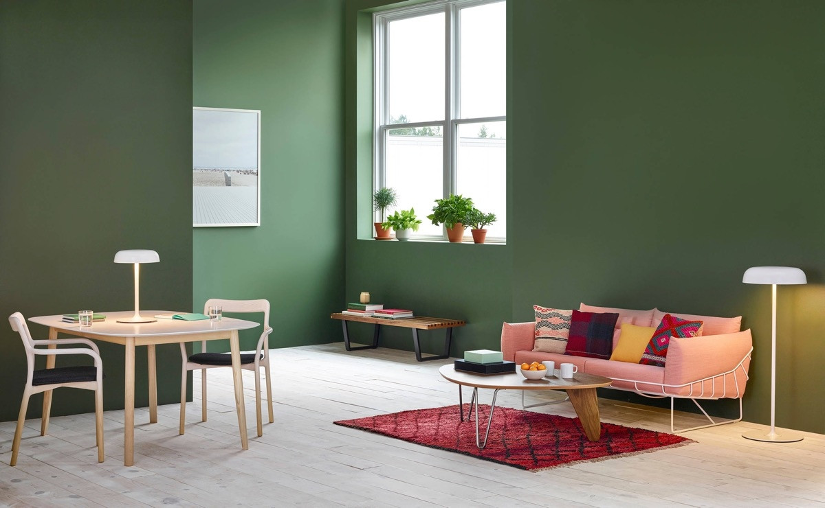 Bức tường màu xanh rêu đậm là ngụ ý của kiến trúc sư nhằm tạo điểm nhấn thu hút trong phòng khách này. Chiếc ghế sofa màu hồng giúp tăng hiệu ứng thị giác, hài hòa với gối và thảm màu đỏ.