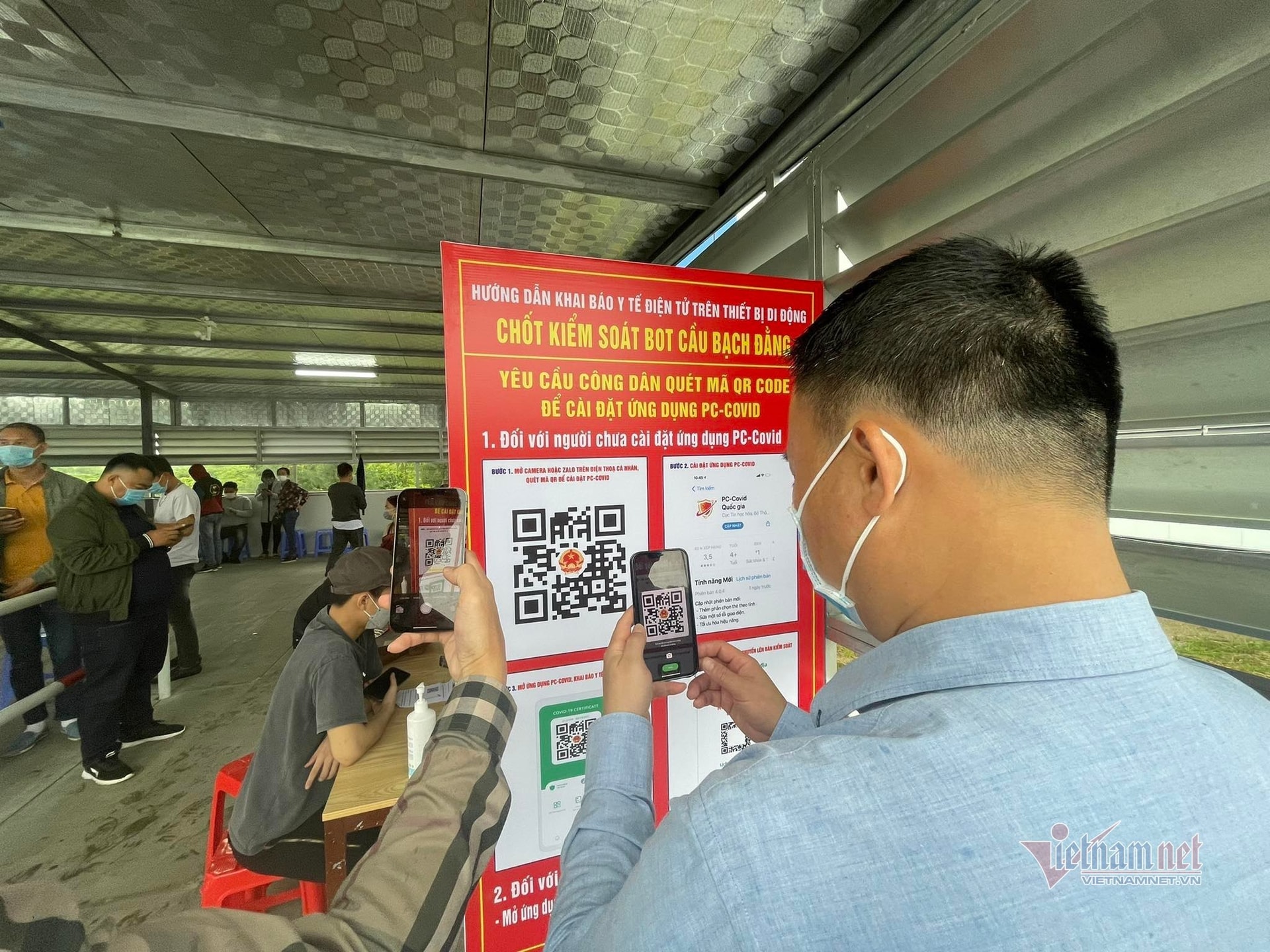 Tài xế ngồi trên xe ung dung khai báo qua máy quét QR dưới lòng đường