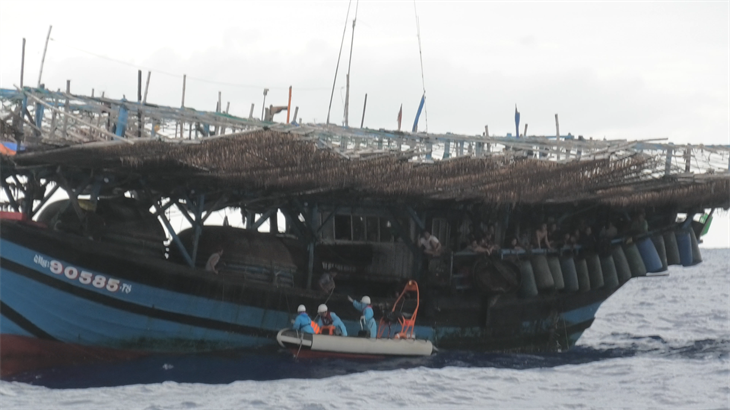 Lực lượng cứu nạn tiếp cận tàu cá QNg 90585 TS đưa thuyền viên Nguyễn Tấn Tính vào bờ điều trị. Ảnh: Quang Định