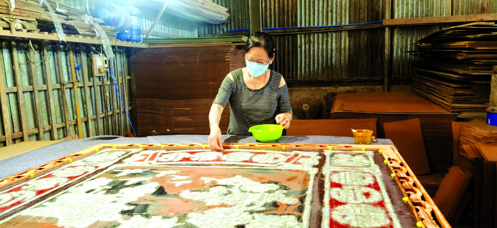 Nghệ nhân Lê Thị Tám - vợ ông Hòa - đang thực hiện bức tranh kiếng khổng lồ: 1m6 x 1m72