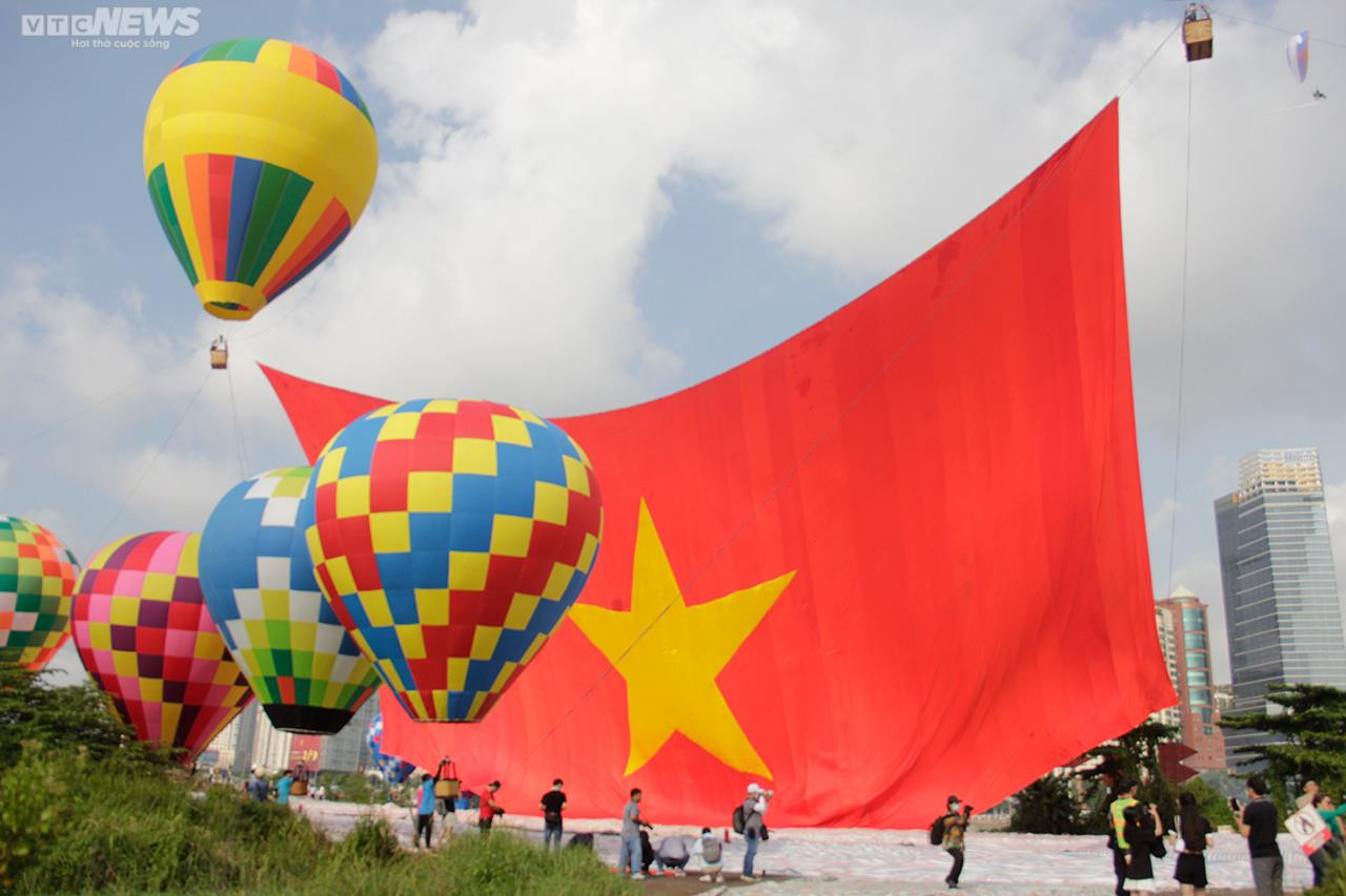 Người dân TP.HCM đội nắng xem khinh khí cầu kéo đại kỳ 1.800 m2 - 1