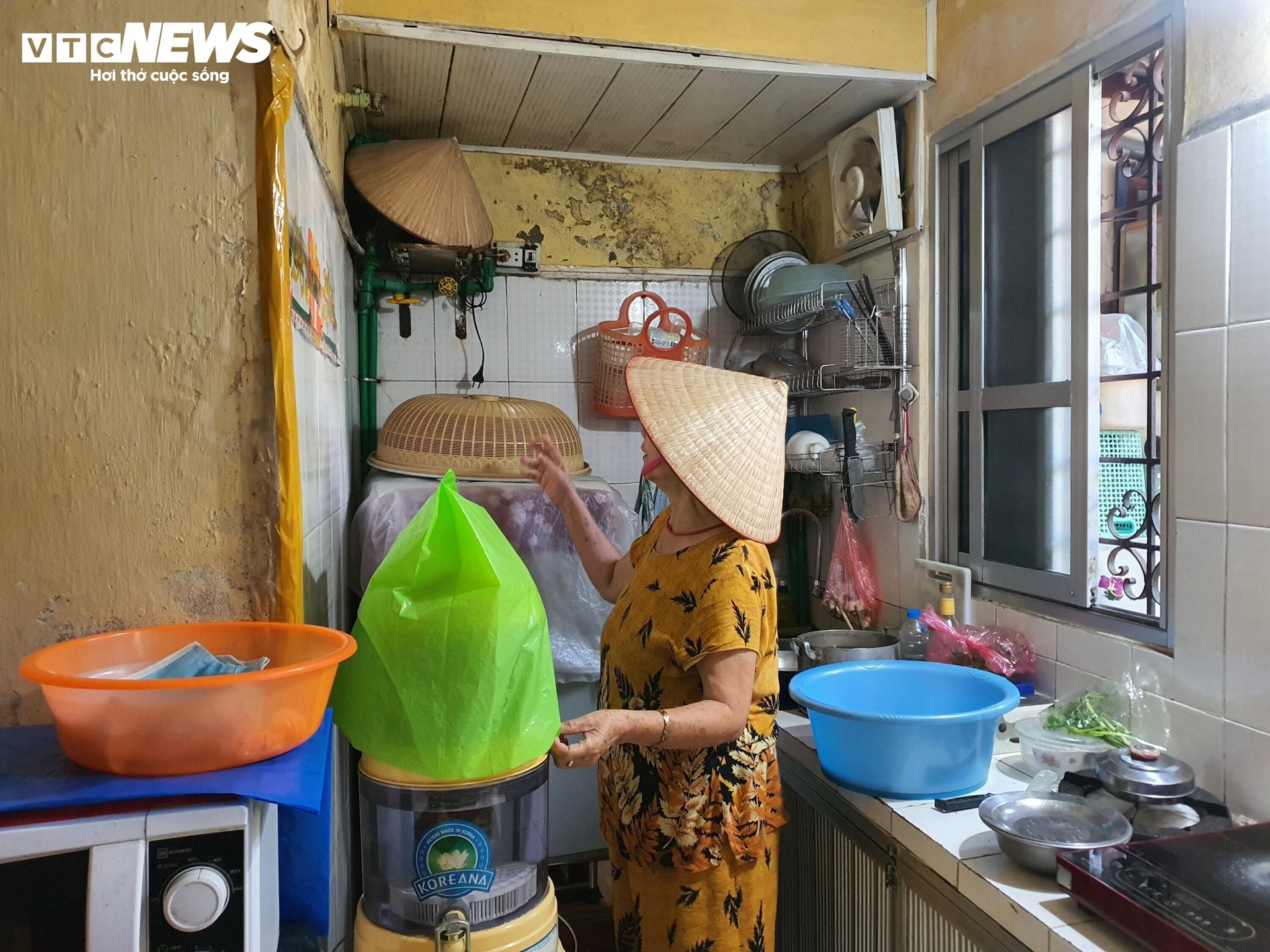 Trong gian bếp của gia đình bà Trần Thị Minh Anh (81 tuổi) nước ngấm từ tầng trên nhỏ giọt xuống hàng ngày, bà buộc phải dùng túi nilon để bọc lại những vật dụng sinh hoạt có trong phòng bếp.