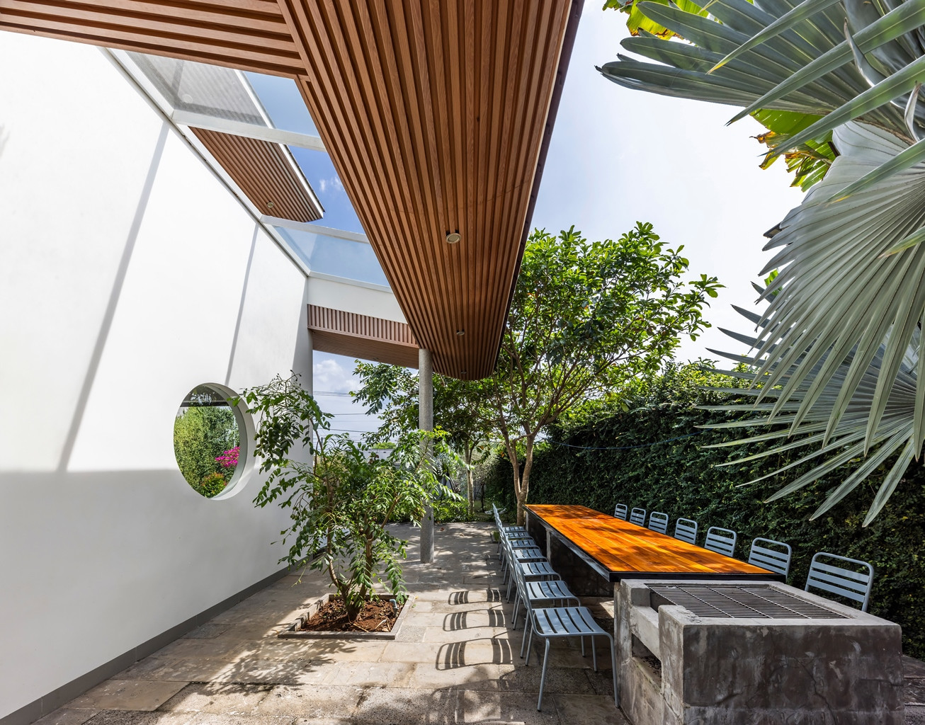 Nhóm thiết kế đã bố trí khu vực mái hiên lớn ở phía trước nhà, kết hợp với cảnh quan cây xanh nhằm tạo ra một không gian rộng rãi, phù hợp để gia chủ ngồi uống trà, trò chuyện với bạn bè, hàng xóm.