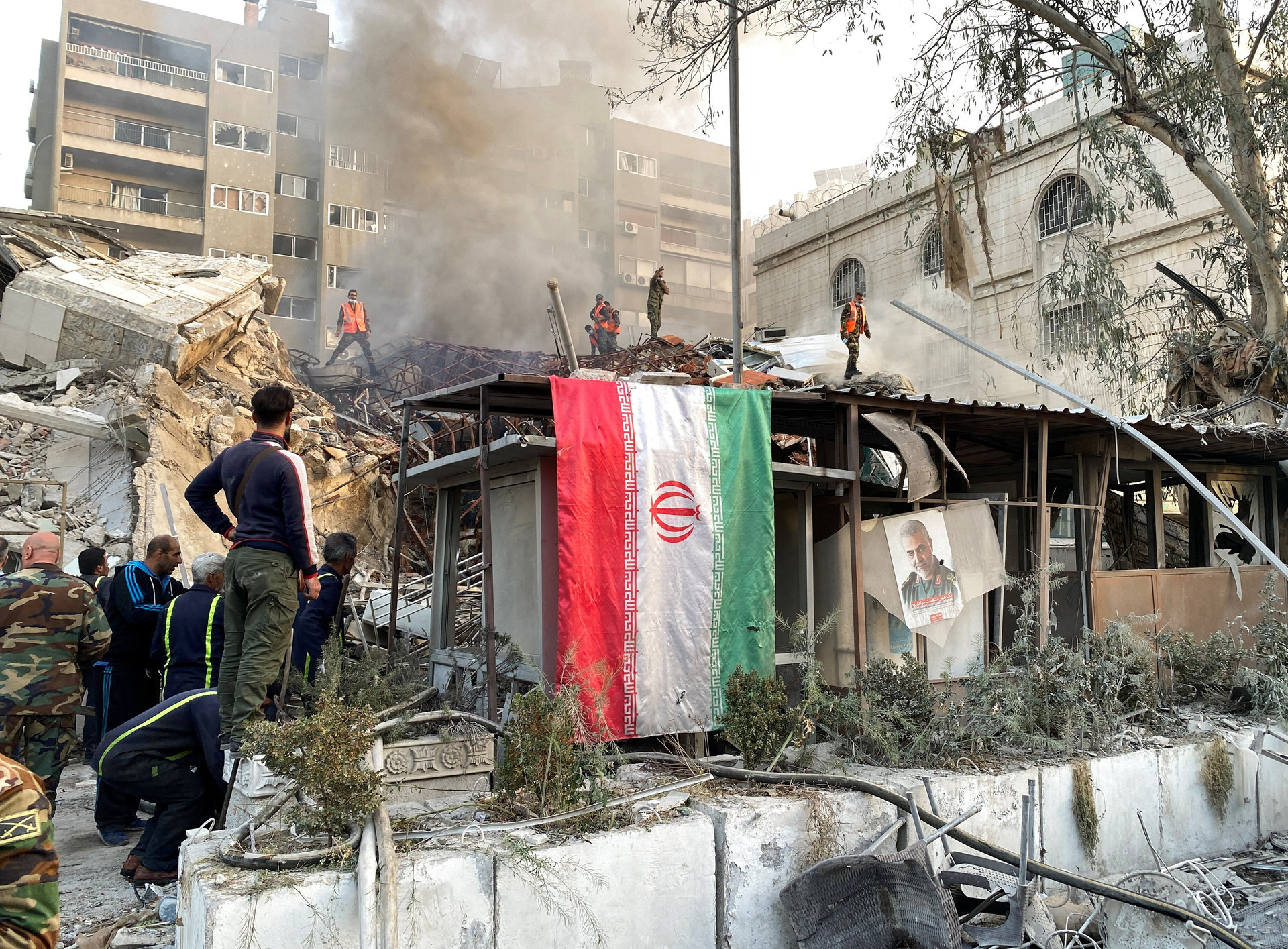 Quốc kỳ Iran treo trước đống đổ nát của đại sứ quan ở Damascus, Syria sau vụ tấn công hôm 1/4. (Ảnh Reuters)