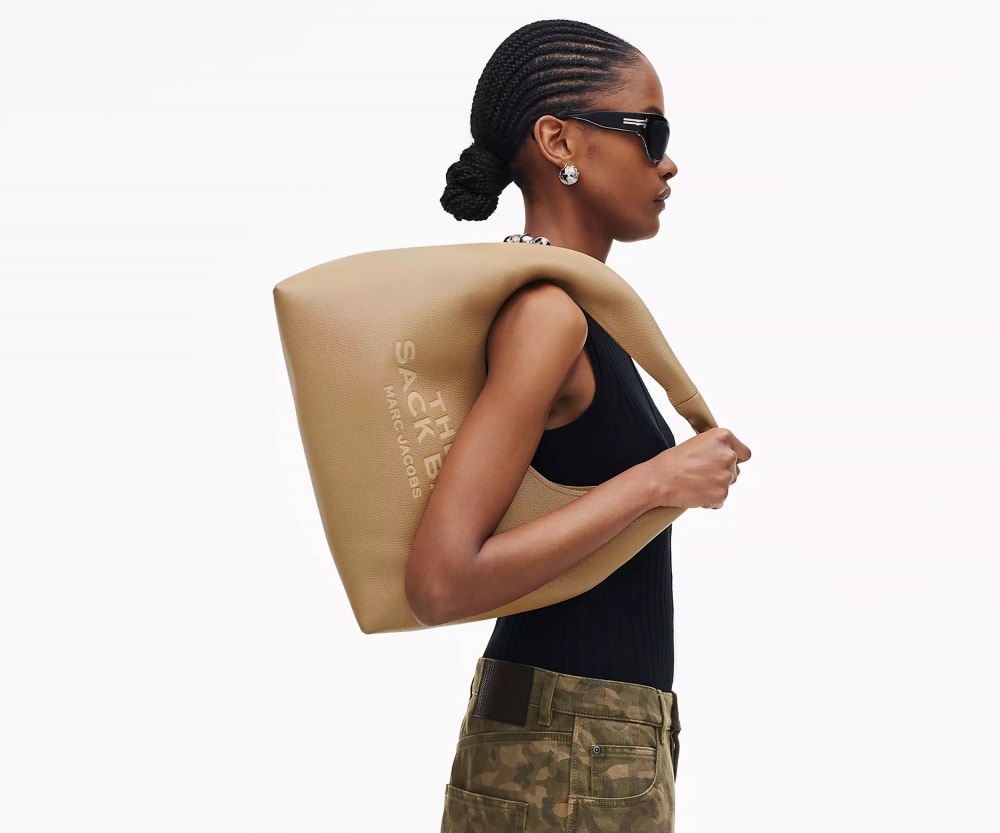 ​Túi The Sack của Marc Jacobs là lựa chọn cá tính cho các quý cô công sở nhờ sự kết hợp giữa tính tiện dụng và phong cách hiện đại. Được chế tác từ da bò cao cấp với đường may nổi bật và logo phía trước, túi mang đến vẻ ngoài hiện đại và chuyên nghiệp. Kích thước rộng rãi cho phép chứa laptop, tài liệu và các vật dụng cá nhân cần thiết cho công việc hàng ngày. Thiết kế với một ngăn chính có khóa kéo an toàn, cùng với túi nhỏ bên trong và túi đính kèm có khóa kéo, giúp sắp xếp đồ đạc một cách ngăn nắp. Dáng hobo cùng dây đeo vai rộng tạo sự thoải mái khi mang, phù hợp cho những ngày làm việc bận rộn hoặc di chuyển nhiều.