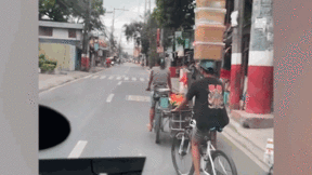 Nam thanh niên đi xe đạp ‘làm xiếc’ với 4 hộp bánh mỳ lớn trên đầu