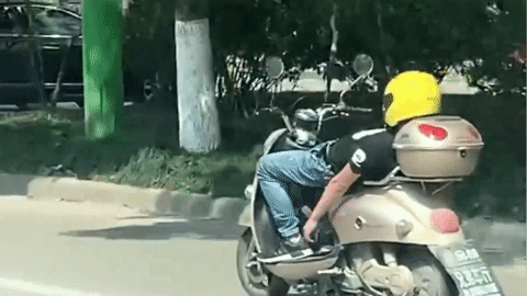 Nam thanh niên vừa nằm vừa lái xe máy khiến người đi đường hoảng hồn