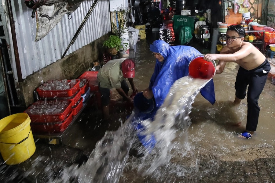 Người dân TPHCM dùng xô tát nước ra khỏi nhà sau cơn mưa lớn
