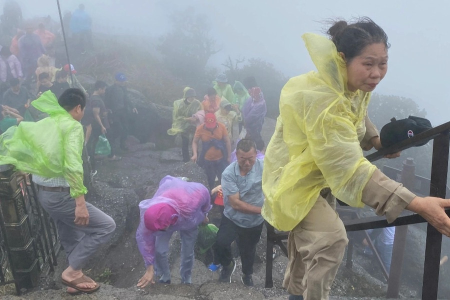 Người dân đội mưa gió chống gậy, vịn lan can lên chùa Đồng Yên Tử